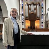 Hans Overkämping steht am Altar in der Josefkirche, hinter ihm sieht man die Orgel und die Kirchenbänke.