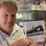 Café-Inhaber Peter Tudyka zeigt die Festschrift zum 50-jährigen Bestehen des TSV Marl-Hüls, in der eine alte Aufnahme der Tribüne im Jahnstadion zu sehen ist.