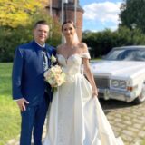 Dr. Michael und Isabell Schymura stehen nach ihrer kirchlichen Trauung in der Hertener Schlosskapelle vor einem Oldtimer.