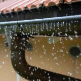 Regen tropft von einer Dachrinne.