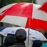 Passanten gehen mit Regenschirmen
