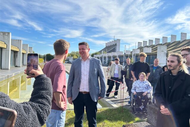 TikTok-Star Levi Penell und Bürgermeister Rajko Kravanja unterhalten sich, während eine der Schaulustigen sie mit ihrem Smartphone filmt.