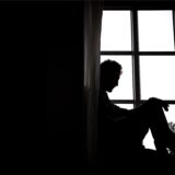Ein Mann sitzt vor einem Fenster.