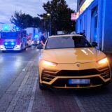 Ein gelber Sportwagen steht auf einem Geh- und Radweg, dahinter Feuerwehrleute im Brandeinsatz in Herten.