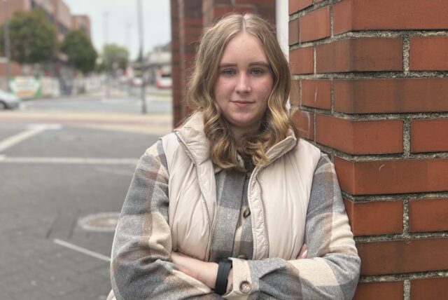 Jasmin Czyszczon lehnt an einem Gebäude und schaut in die Kamera.