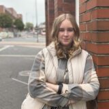 Jasmin Czyszczon lehnt an einem Gebäude und schaut in die Kamera.