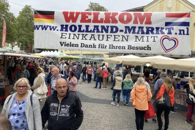 Hollandmarkt auf dem Tigg, über den Ständen hängt ein Banner: „Welkom Holland-Markt Einkaufen mit Herz. Vielen Dank für Ihren Besuch“
