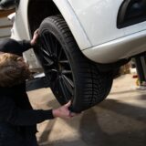 Ein Mechatroniker wechselt den Reifen eines Autos in einer Werkstatt.