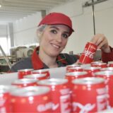 Frau hält in eine Produktionshalle eine Coca-Cola-Dose in der Hand