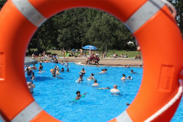 Blick durch einen Schwimmring auf die Besucher im Schwimmbecken des Freibards Hardenberg in Dortmund-Deusen.