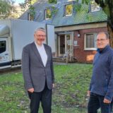 Propst Karl Kemper und Michael Plester vom Kirchenvorstand der Großpfarrei St. Peter stehen vor der Propsteipfarrei in Recklinghausen. Im Hintergrund ein Umzugswagen.