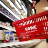 Rewe-Einkaufskorb in einer Rewe-Filiale vor einem Regal.