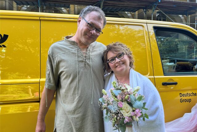 Ein Mann und eine Frau stehen vor einem gelben Transporter von der Deutschen Post.