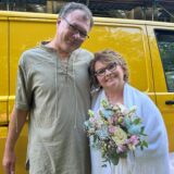 Ein Mann und eine Frau stehen vor einem gelben Transporter von der Deutschen Post.