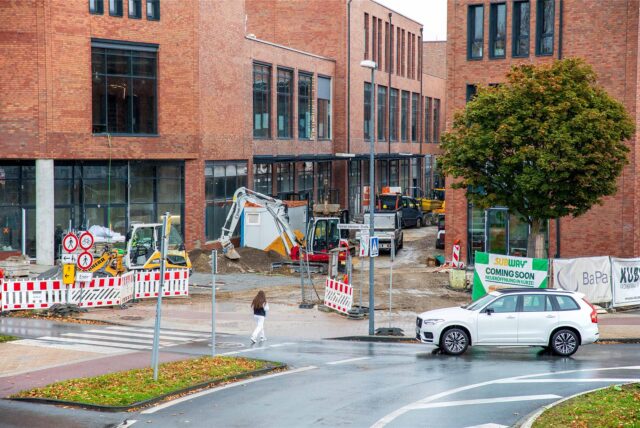 Die Baustelle der Hertener Höfe: Große Gebäude, von außen verklinkert, umlagert von mehreren Baggern und anderen Baumaschinen.