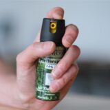 Eine Person hält eine Pfefferspraysprühdose in die Kamera.