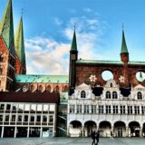Unser Mitarbeiter Werner Koppe steht in der Lübecker Alfstraße, wo der Recklinghäuser Hans Reckmann lange gewohnt hat. Links sieht man das Lübecker Rathaus am Markt.
