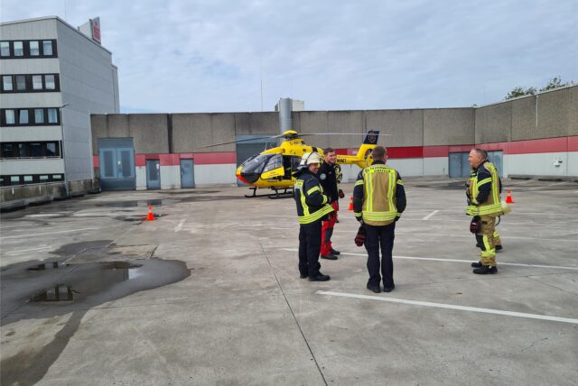 Ein Rettungshubschrauber auf einem Parkdeck in Datteln, davor stehen Feuerwehrleute.