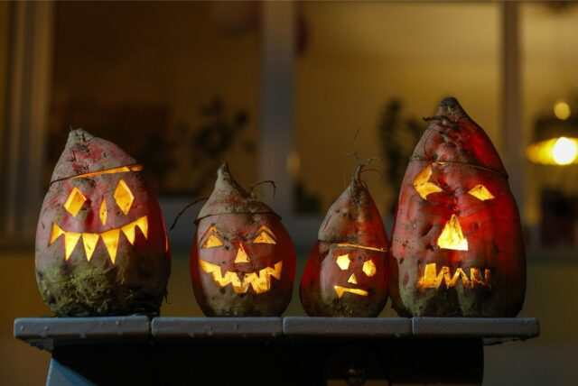 Vier Halloween-Kürbislaternen mit grinsenden Fratzen.