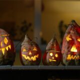 Vier Halloween-Kürbislaternen mit grinsenden Fratzen.