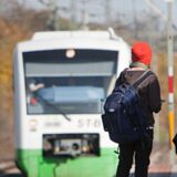Schüler stehen an einem Bahnsteig, während ein Zug einfährt.