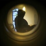 Durch den Türspion kann der Anwohner eine dunkle begleitet Person erkennen.