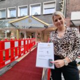 Eine Frau steht vor einer Baustelle und drückt eine Klingel.