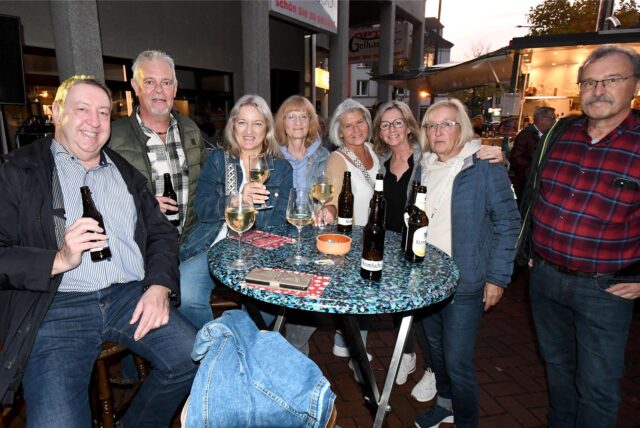 Eine Gruppe von Männern und Frauen sitzt und steht bei letzten  Feierabendmarkt des Jahres 2024 in Herten-Langenbochum an einem Tisch.
