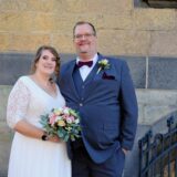 Das Brautpaar Nadine Bruckwilder und Fabian Bösing steht in feierlicher Kleidung vor dem Rathaus in Recklinghausen.