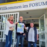 Drei Personen stehen vor einem Eingang
