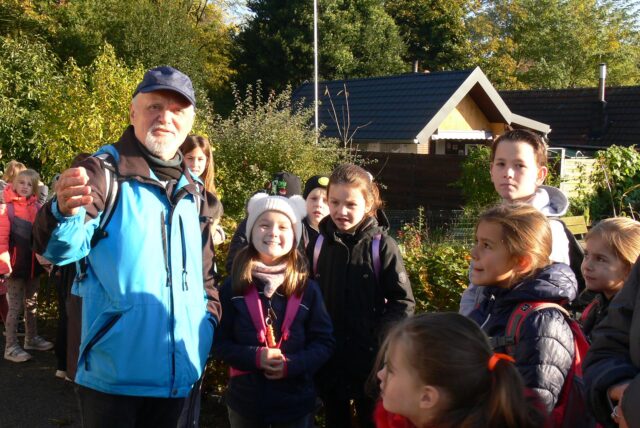 Fachberater Wolfgang Kniep mit der Gruppe vor der Gartenparzelle von Han-Jürgen Husmann.