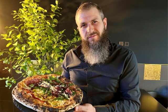 Gastronom Marcel Strozyk vom Pizza-Restaurant „450 Degrees“ in Dortmund-Mengede hält eine Pizza Napoli in die Kamera.