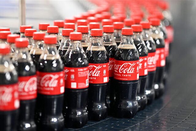 Coca-Cola-Flaschen auf dem Fließband einer Produktionshalle.