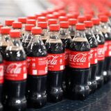 Coca-Cola-Flaschen auf dem Fließband einer Produktionshalle.