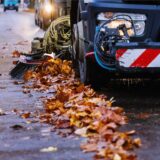 Eine Kehrmaschine fährt und kehrt Laub zusammen