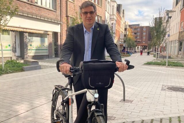 Patrick Berner im dunklen Anzug mit seinem Pedelec in der Hertener Fußgängerzone.