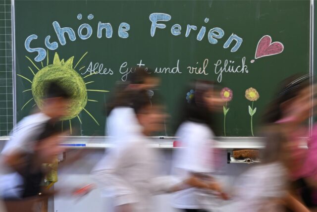 Zu Beginn der Herbstferien in NRW Schulkinder laufen an der Tafel vorbei.