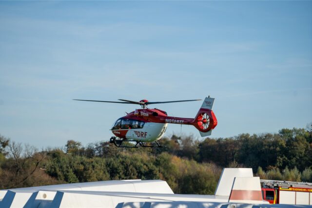 Ein Rettungshubschrauber fliegt über den Segelflugplatz Kamen-Heeren. Im Hintergrund Rettungsfahrzeuge.