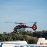 Ein Rettungshubschrauber fliegt über den Segelflugplatz Kamen-Heeren. Im Hintergrund Rettungsfahrzeuge.
