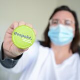 Melanie Seibold vom Ärztenetz Reutlingen zeigt in einer Arztpraxis einen Button mit der Aufschrift „Respekt füreinander miteinander“.