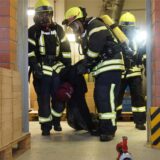 Feuerwehrleute schleppen eine hilflose Person aus einem Haus.