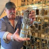 Wolfgang Dudek steht mit in einer Grubenlampe in der Hand vor einer Vitrine mit vielen weiteren.