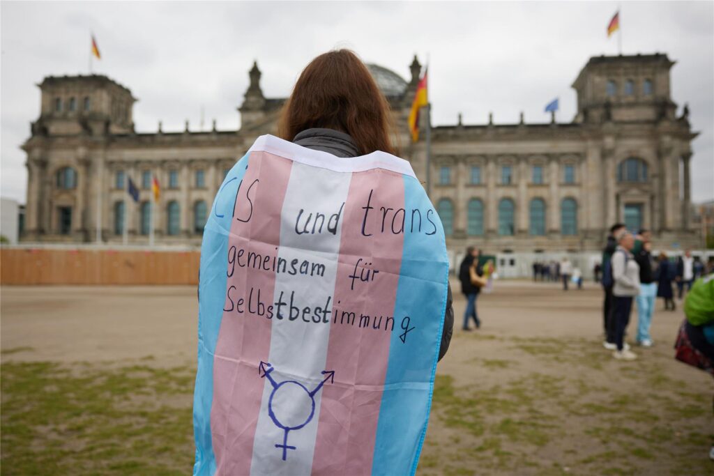Eine Teilnehmerin steht bei einer Protestveranstaltung gegen das Selbstbestimmungsgesetz von Frauengruppen mit einer Transgender-Pride-Flagge vor dem Bundestag. Eine Teilnehmerin steht bei einer Protestveranstaltung gegen das Selbstbestimmungsgesetz von Frauengruppen mit einer Transgender-Pride-Flagge vor dem Bundestag.