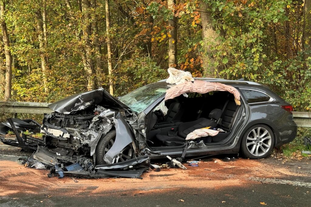 Ein stark zerstörtes Auto hat keine Fahrertür mehr.