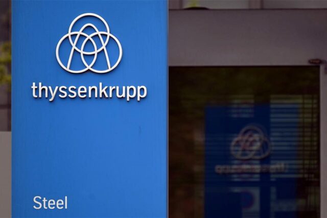 Das Thyssenkrupp-Logo steht vor einer Werksanlage.