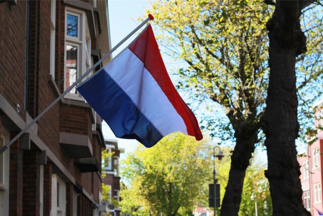 Eine Flagge der Niederlande weht an einem roten Backsteinhaus.