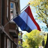 Eine Flagge der Niederlande weht an einem roten Backsteinhaus.