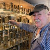 Wolfgang Dudek aus Marl greift nach einer Grubenlampe, die mit vielen weiteren in einer Vitrine ausgestellt ist.