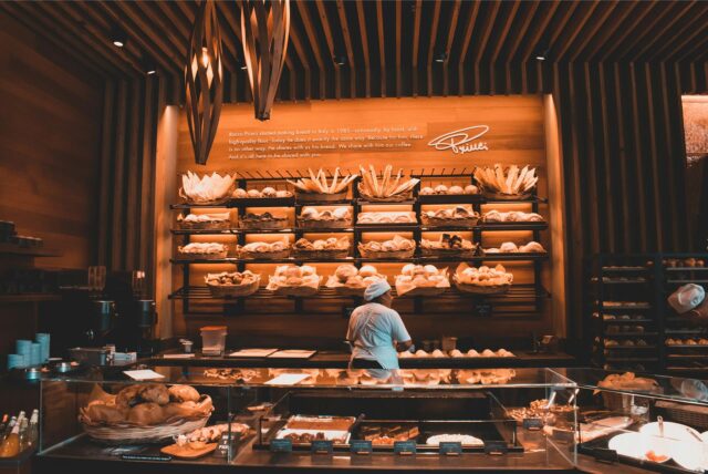 Eine Mitarbeiterin steht in einer Bäckerei vor der Auslage.