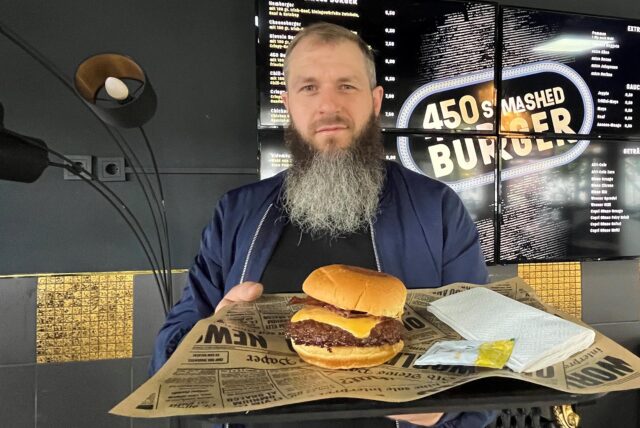 Inhaber Marcel Strozyk hält einen seiner Burger in die Kamera.